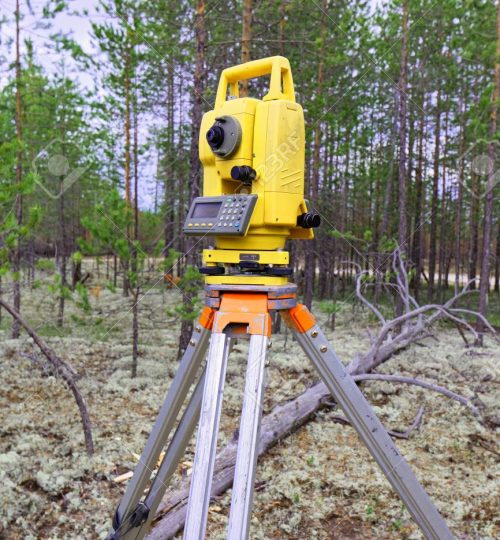 Modern threadbare electronic total station mounted on tripod in field conditions in the taiga